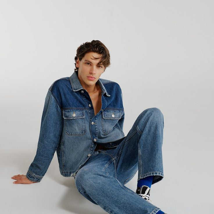Person wearing a denim outfit sitting on a white background